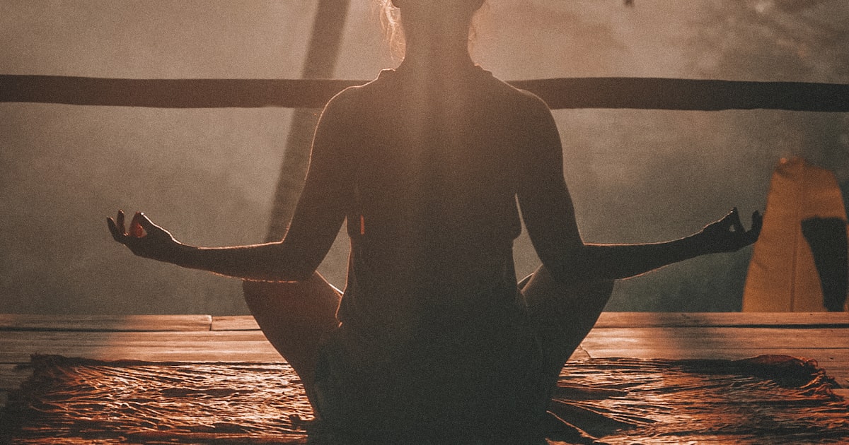 Silhouette of a woman meditating in lotus position at sunset, representing the calm after working through perimenopause rage
